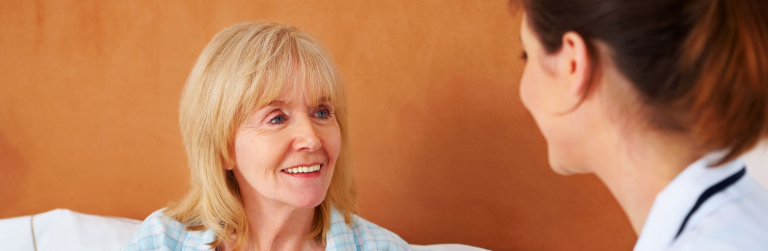 Smiling elderly woman conversing with healthcare professional.