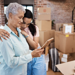 Shot of a senior woman looking at a photograph with her daughter while packing boxes on moving day