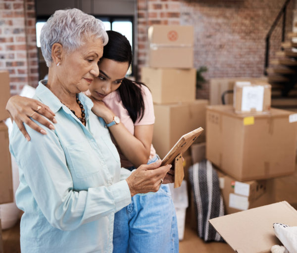 Shot of a senior woman looking at a photograph with her daughter while packing boxes on moving day