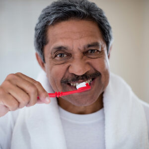 Portrait of senior man brushing teeth in bathroom at home